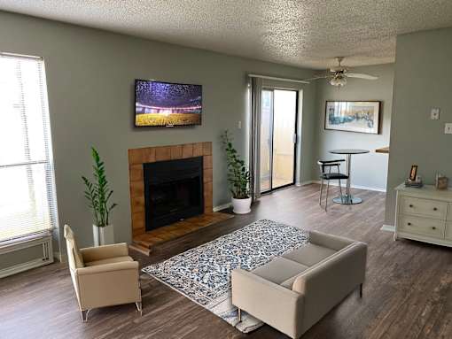 A living room with a fireplace and a television mounted above it.