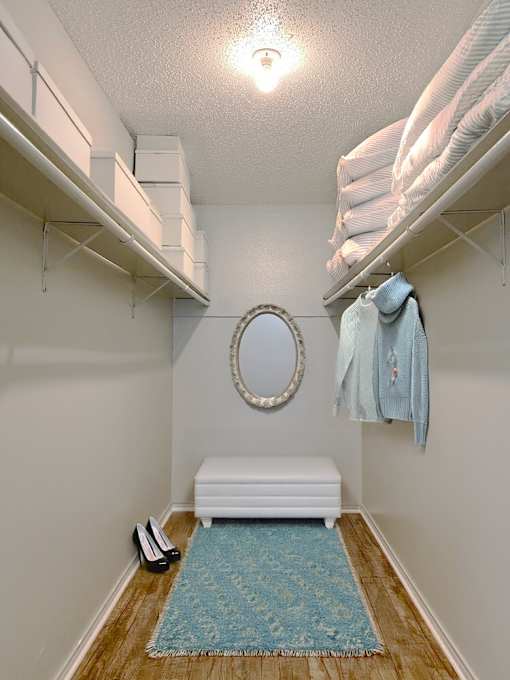 A small room with a round mirror and a white bench.