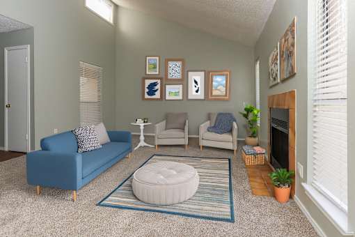 A living room with a blue couch, a white ottoman, and a fireplace.