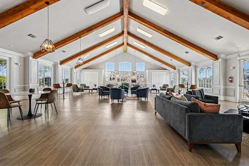 A spacious living room with a grey couch and wooden floors.