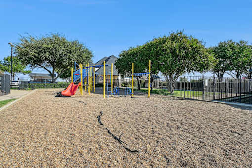 A playground with a yellow swing set and a red slide.