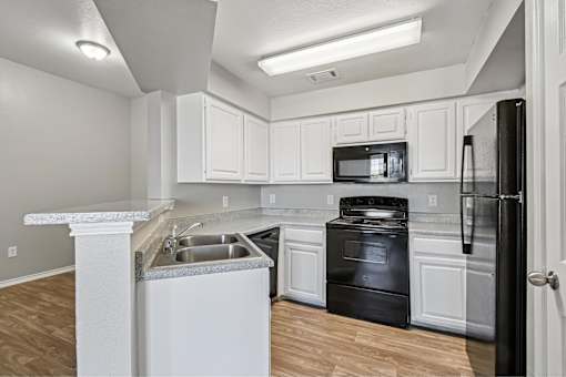 A kitchen with black appliances and white cabinets.