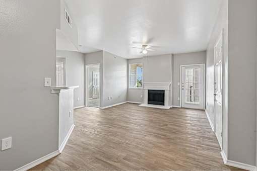 A spacious living room with wood flooring and a fireplace.