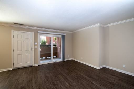 A room with a white door and a sliding glass door leading to a balcony.