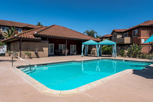 A swimming pool surrounded by a patio and umbrellas.