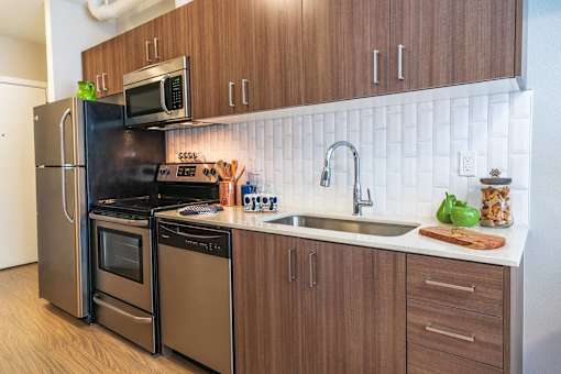 A kitchen with a black refrigerator and brown cabinets.