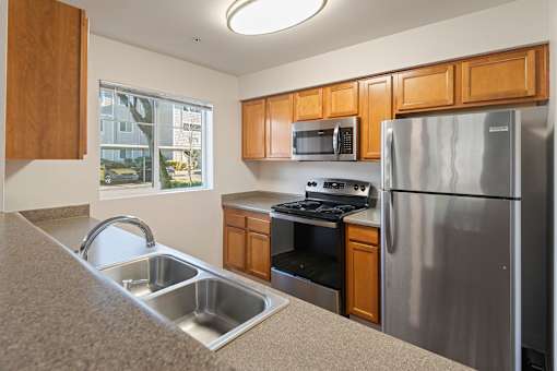 A kitchen with a stainless steel refrigerator, microwave, and oven.