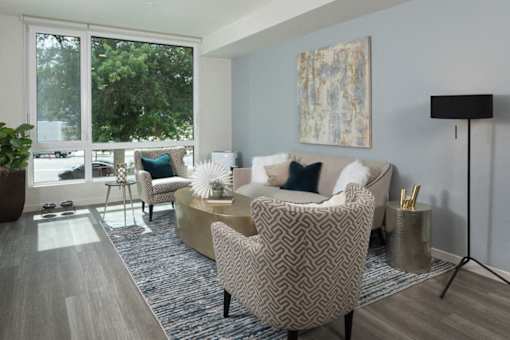 A living room with a patterned chair and a couch with a blue pillow. at Ravello Apartments, Washington, 98052