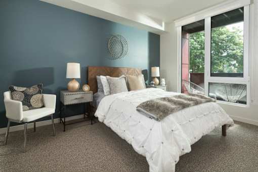 A bedroom with a large bed and a chair. at Ravello Apartments, Redmond, Washington