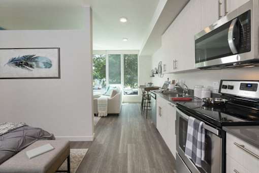 A modern kitchen with a grey floor and white cabinets. at Ravello Apartments, Washington