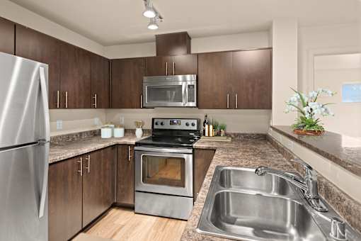 A modern kitchen with a stainless steel refrigerator, oven, and sink.