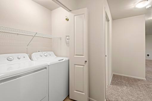 A laundry room with a washer and dryer and a white door.