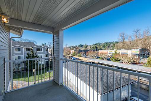 A balcony with a view of a parking lot and buildings.