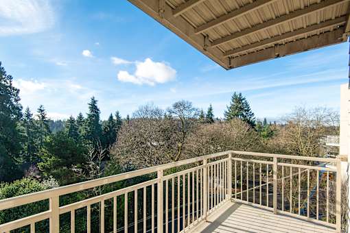 A balcony with a railing overlooks a wooded area.