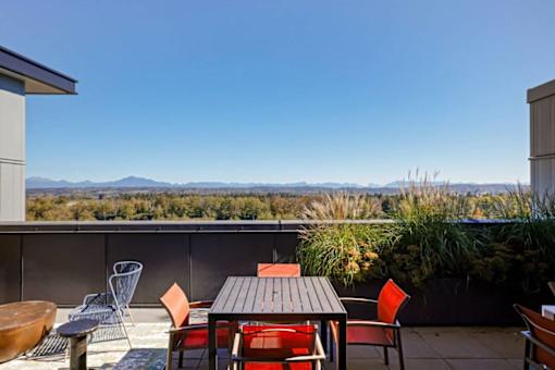 A patio with a table and chairs overlooking a mountainous landscape. at Riverfront Everett, Everett, 98201