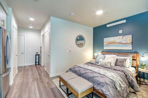 A bedroom with a bed, bench, and a painting on the wall. at Ravello Apartments, Washington