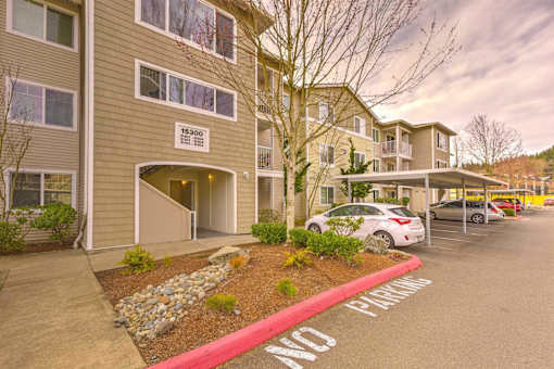 A parking lot in front of apartment building with a red curb and a sign  at Valley Springs Apartments, Renton, Washington