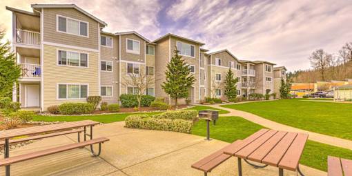 Apartment complex with a grassy area and picnic tables in front at Valley Springs Apartments, Renton