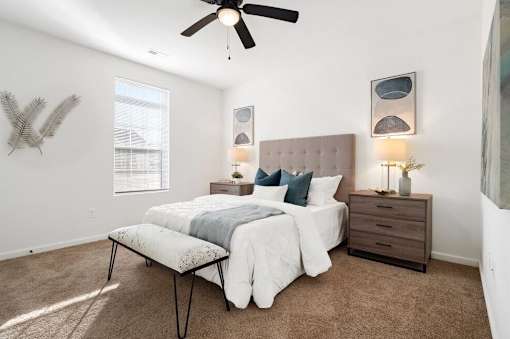 A bedroom with a bed, nightstand, and a ceiling fan.
