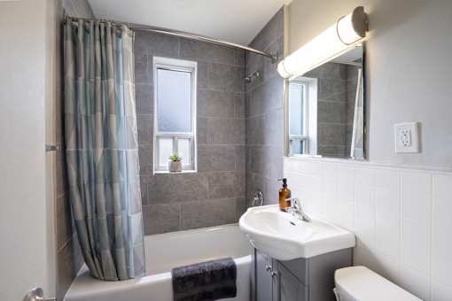 A bathroom with a white sink and a window with a curtain.