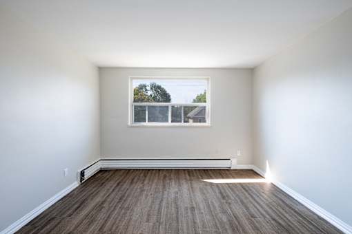 A room with a window and wooden flooring.