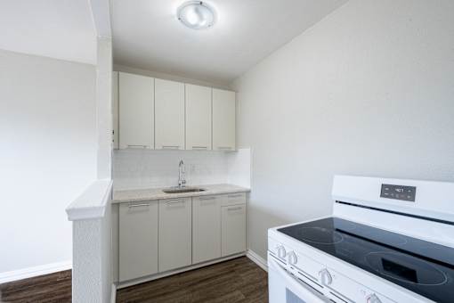 A white kitchen with a stove top oven.