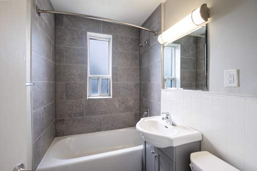 A bathroom with a white tub, sink, and toilet.