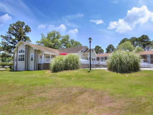 A house with a red awning is surrounded by greenery and a clear blue sky.
