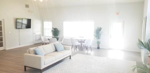 A living room with a white couch and a television on the wall.