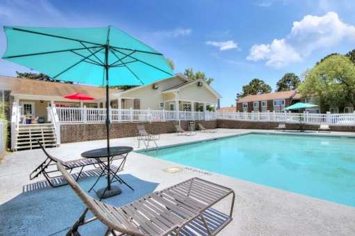 A pool with a table and chairs and a blue umbrella.