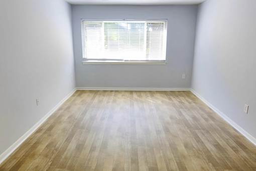 A room with wooden flooring and a window with blinds.