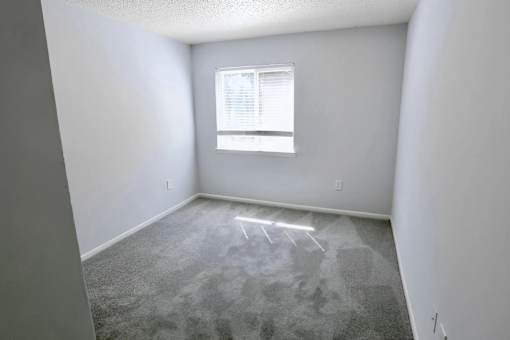 A room with a window and carpeted floor.