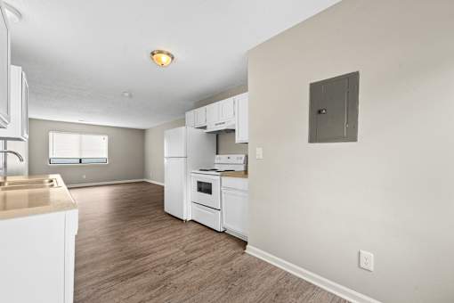 A kitchen with white appliances and wooden floors.