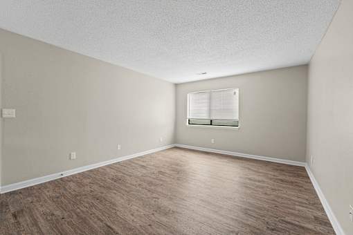 A room with wooden flooring and a window with blinds.