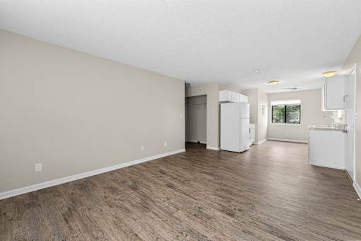 A spacious room with wooden flooring and white walls.