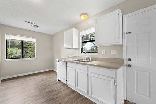 A kitchen with white cabinets and a window.