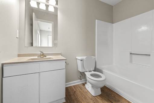 A white bathroom with a toilet, sink, and mirror.