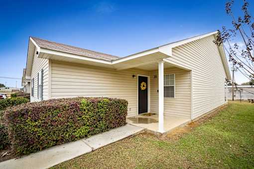 A residential building with a door and a sidewalk leading up to it.