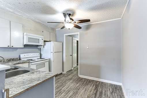 A kitchen with a refrigerator, microwave, and oven.