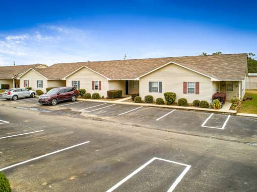 A parking lot in front of a residential building with cars parked in the front.