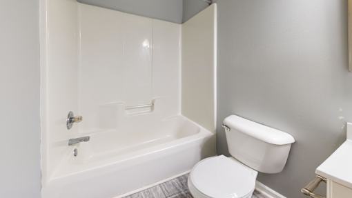 A white toilet sits next to a bathtub in a bathroom.