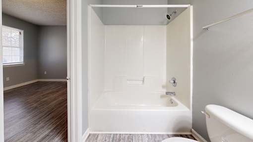 A white bathroom with a tub and toilet.