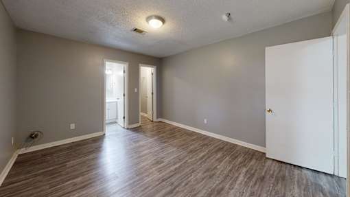 A room with wooden flooring and white walls.