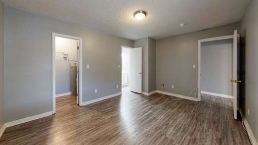 A room with wooden flooring and three open doors.