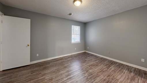 A room with a white door and a window with a wooden floor.