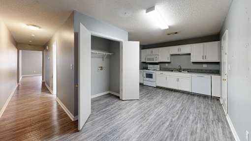 A kitchen with white cabinets and a grey floor.