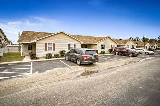 A parking lot with a few cars and residential buildings in the background.