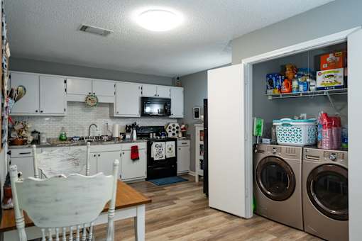 A small kitchen with a table and chairs with a laundry closet beside it.