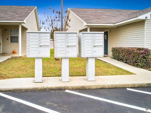 Three mailboxes are standing on a sidewalk in front of a residential building.
