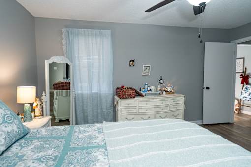 A bedroom with a bed, dresser, and a mirror.